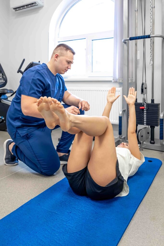 woman doing gymnastics with help of his young physical therapist.