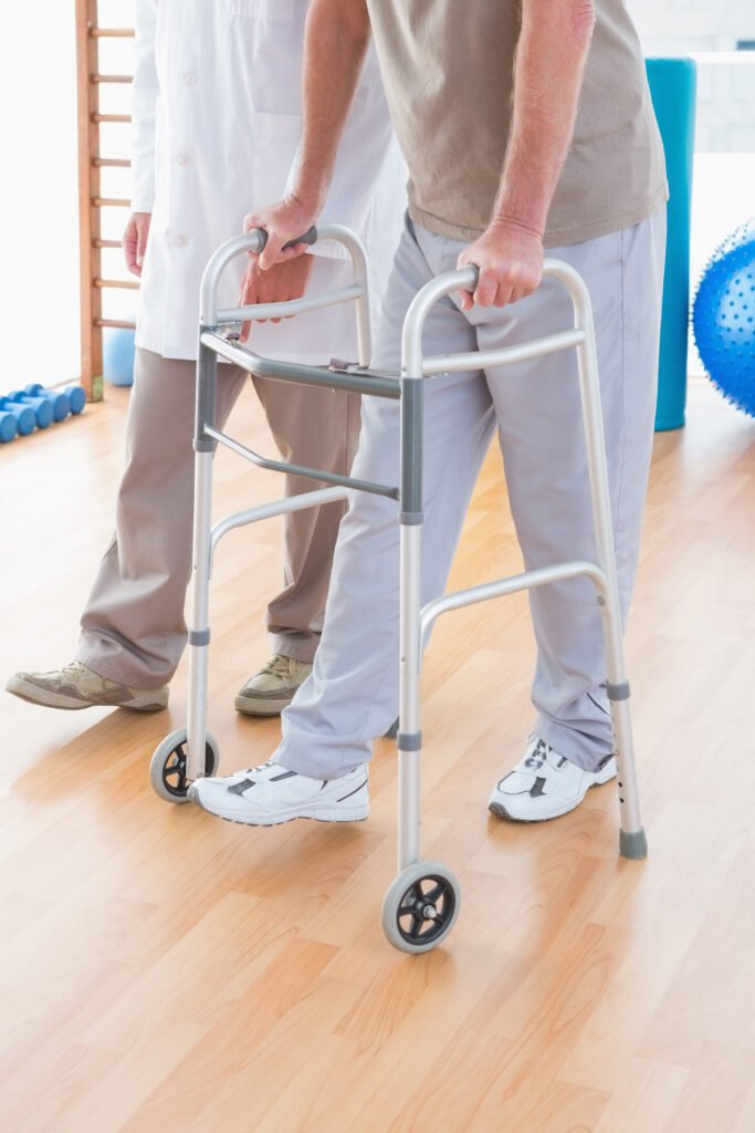 senior man on zimmer frame with therapist in fitness studio
